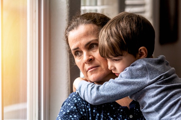 Sad nurse holding son looking out of window