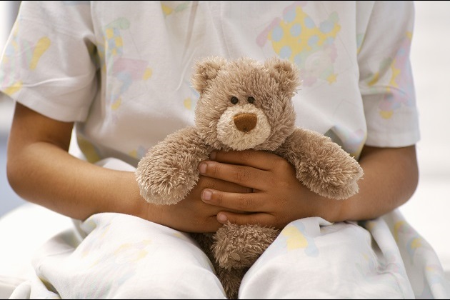 child hands in hospital gown holding teddy