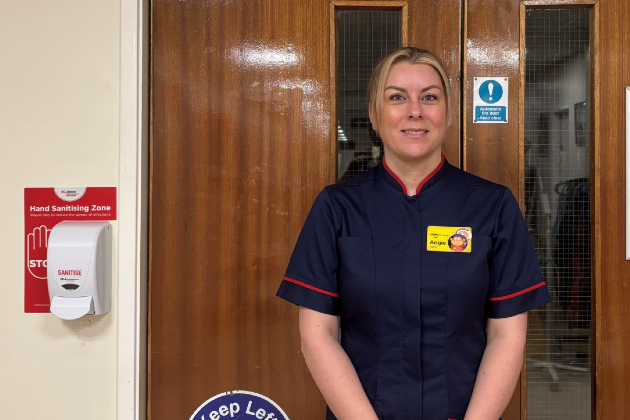 Angela, outpatient team leader in uniform stood outside brown double doors 