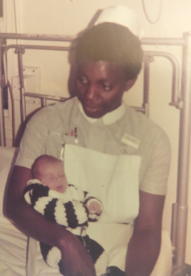 Allyson in uniform in hospital holding a baby 1970s