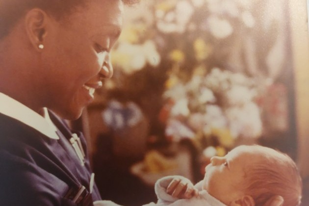 Allyson Williams as community midwife in 1980s holding a baby