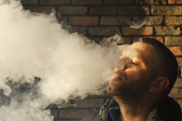 Man smoking blowing out lots of smoke