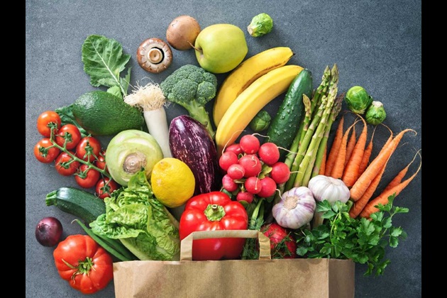 Fruit and vegetables spill out of a brown paper bag
