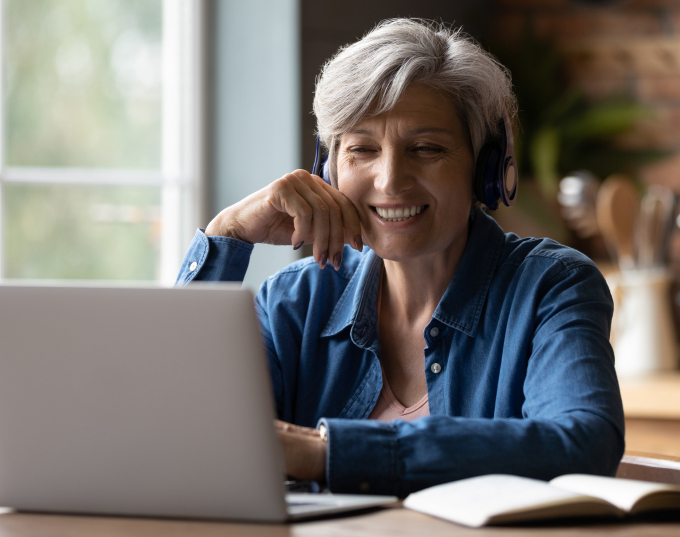 A woman wearing headphones sits at her laptop