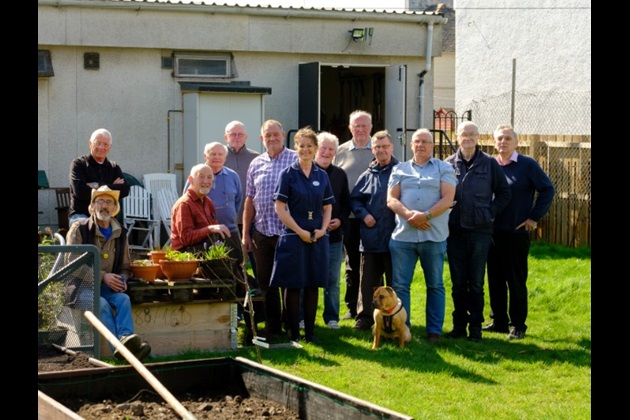 Nurse Sarah Everett and members of Men's Shed Govan pose for a group shot in the garden outside the shed
