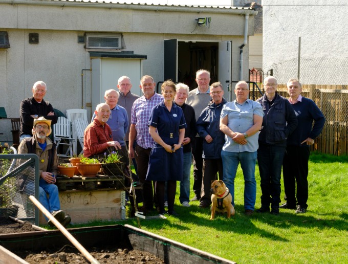 Nurse Sarah Everett and members of Men's Shed Govan pose for a group shot in the garden outside the shed