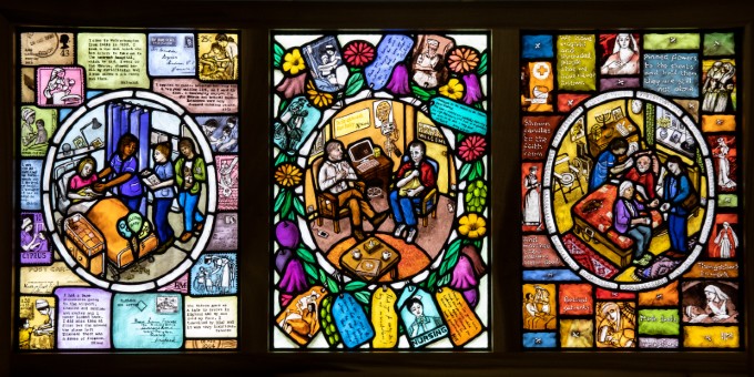 Triptych stained glass window depicting the role nurses play in birth, illness and death