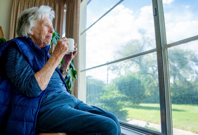 Stock image shows care home resident looking out of window at sunny garden