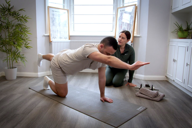 A physiotherapist instructing a patient on how to perform the superman Pilates exercise