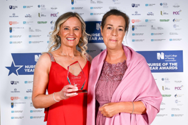 ANP in district nursing Maria Betts at the RCN Northern Ireland Nurse of the Year awards. She is smiling while holding a glass award and wearing a red dress