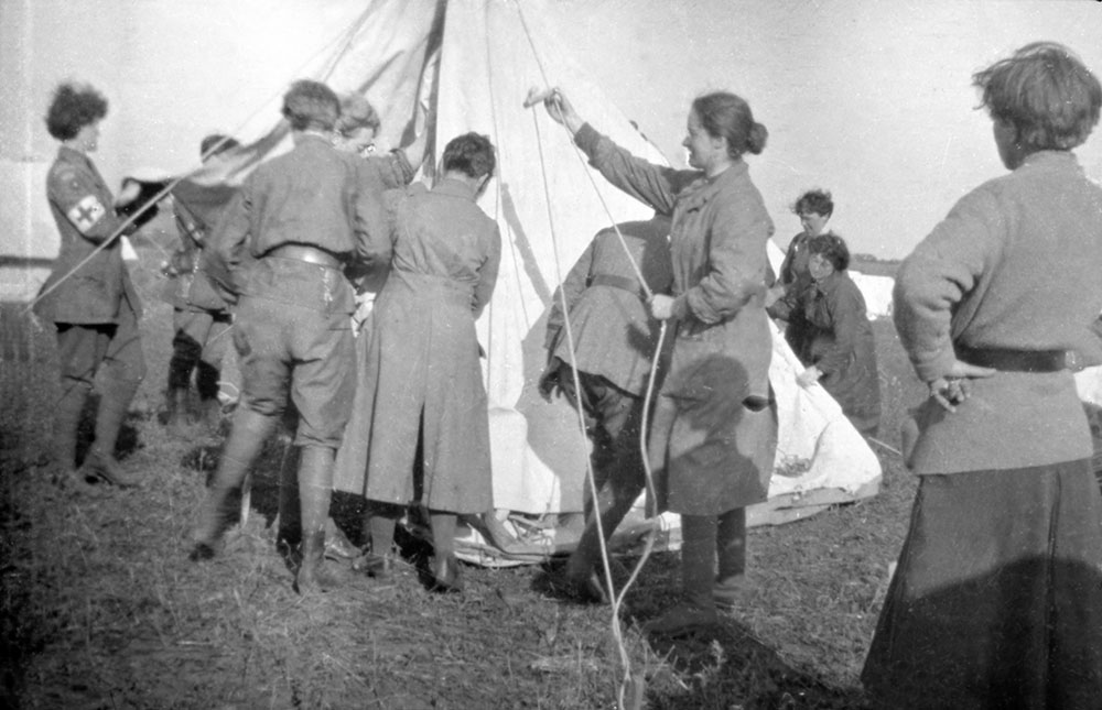 Women of the Scottish Women’s Hospitals group pitching Bell tents including some in VAD uniform (with armband), Romania.
