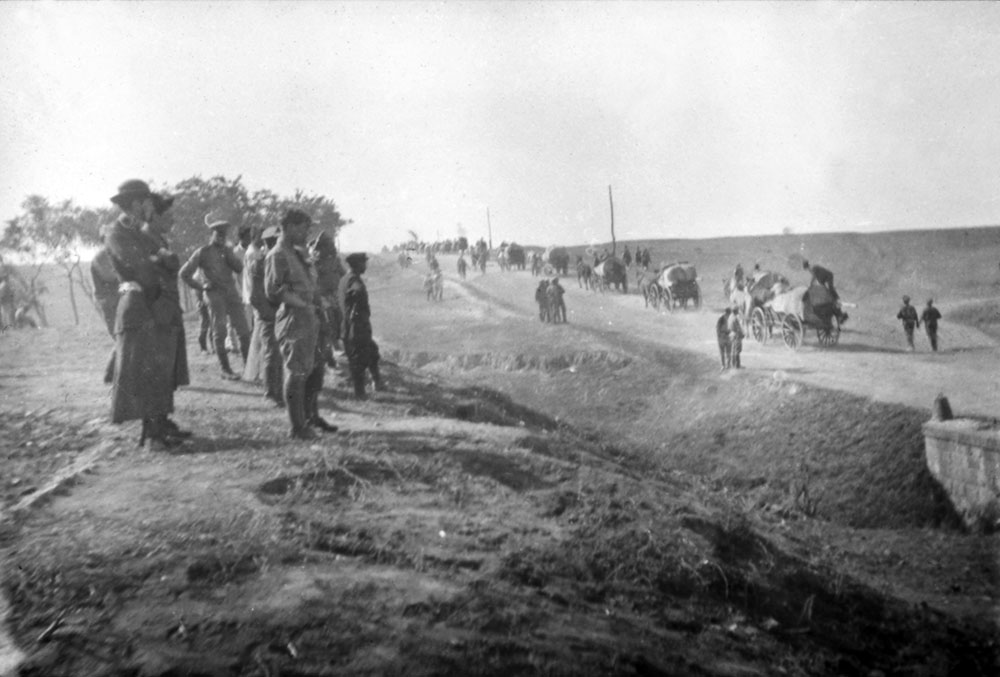 A view of road with staff watching either soldiers on the move or refugees fleeing, Romania.