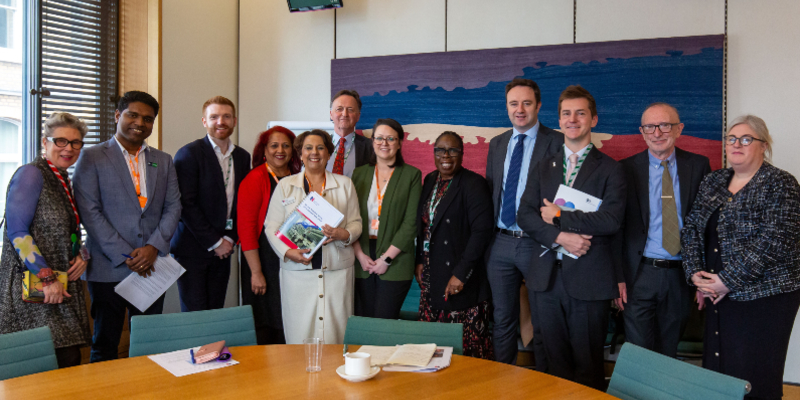 RCN members and staff including Nicola Ranger and Bejoy Sebastian are seen among a group shot inside a building at Westminster, where a meeting about corridor care took place. All are facing the camera and smiling.
